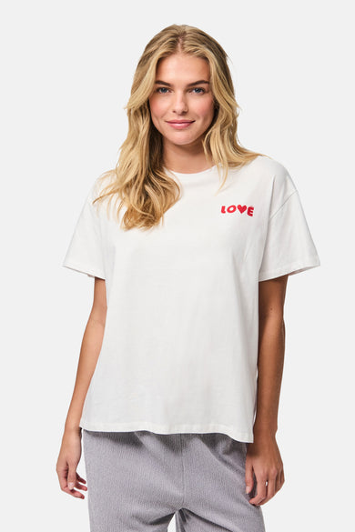 T-shirt blanc à manches courtes de PIECES®, avec du texte "LOVE" rouge dessus, porté avec un pantalon gris.