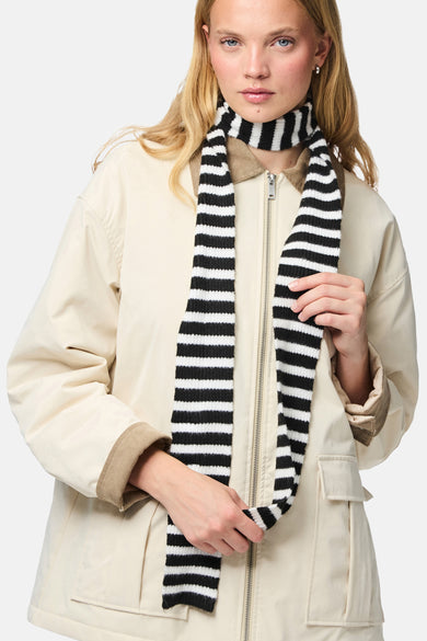 Écharpe rayée noir et blanc de PIECES®, portée par un modèle avec un manteau beige.