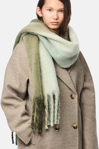 Manteau d'hiver vert de Pieces avec des franges, porté sur une veste beige.