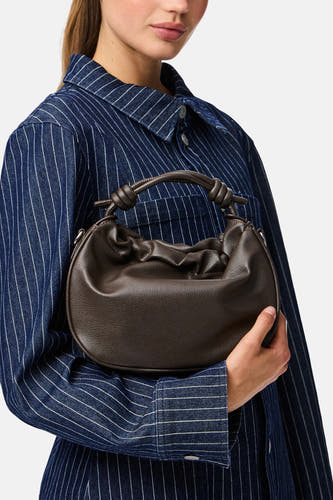 Sac à main marron de PIECES, tenu par une personne portant un chemisier rayé bleu.