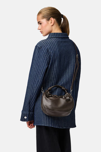 Sac à main brun de PIECES®, de forme ronde et courte poignée, porté sur un chemisier rayé.