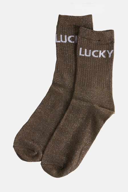 Chaussures de kaki PIECES®, avec une texture brillante et le mot "LUCKY" en lettres blanches.