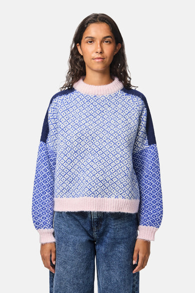 Sweat-shirt multicolore à col rond de PIECES, avec un motif à carreaux et des bordures rayées roses, porté avec un jean bleu.