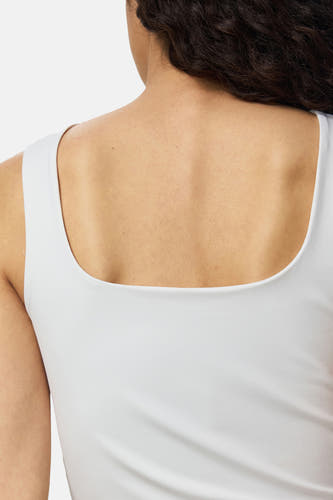 Witte body van PIECES® met ronde halslijn, strakke pasvorm, rugzijde in close-up, gladde stof, model met donker krullend haar
