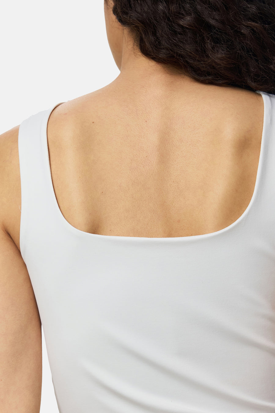 Witte body van PIECES® met ronde halslijn, strakke pasvorm, rugzijde in close-up, gladde stof, model met donker krullend haar