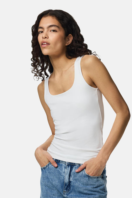Witte body van PIECES® met ronde hals en smalle bandjes, gedragen met blauwe jeans, zijprofiel.