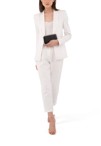 Sac à dos noir de PIECES®, porté avec une veste blanche pour femme et des sandales transparentes.