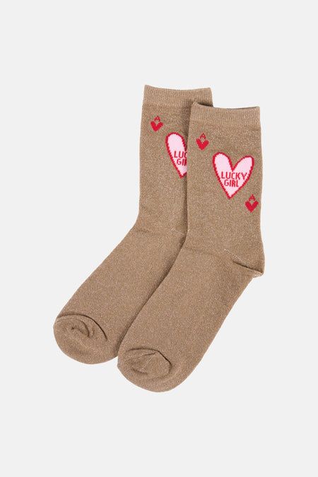 Chaussettes beiges à paillettes de PIECES® avec cœur rose, inscription 'LUCKY GIRL' et carreaux rouges, présentées avec une étiquette blanche.