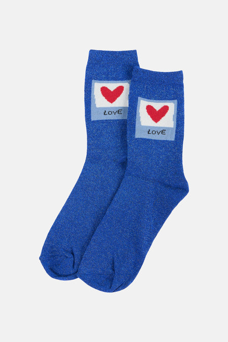 Chaussettes bleu pailleté de PIECES® avec un cœur rouge et le texte 'LOVE' inversé sur un fond blanc et bleu clair.