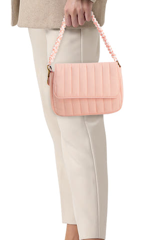 Sac à bandoulière matelassé rose de PIECES® avec anse tressée blanche et orange, tenu par une personne.