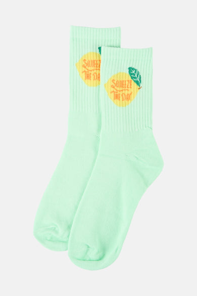 Chaussettes vertes de PIECES®, avec une texture côtelée et un imprimé de citrons avec le texte "Squeeze the day".