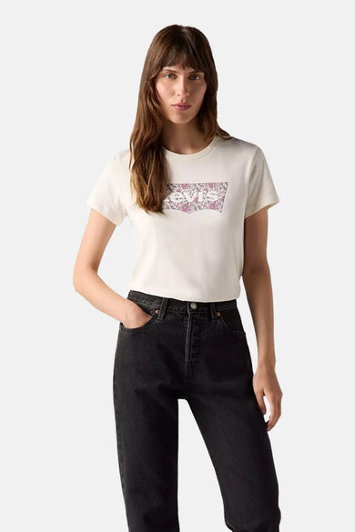 T-shirt ecru à manches courtes de Levi's, avec un logo fleuri sur la poitrine, combiné avec un jean noir.