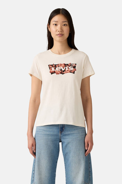 T-shirt beige à manches courtes de Levi's, avec imprimé de fleurs sur le logo. Porté avec un jeans bleu.