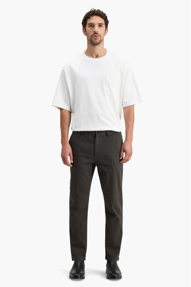 Grijze chino van SCOTCH & SODA, gedragen met een wit T-shirt en zwarte laarzen.