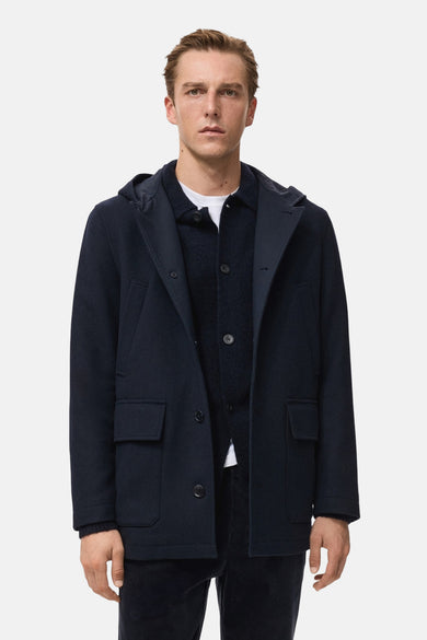 Manteau court bleu marine de MANGO, vu de l'arrière avec un capuchon et une texture lisse.