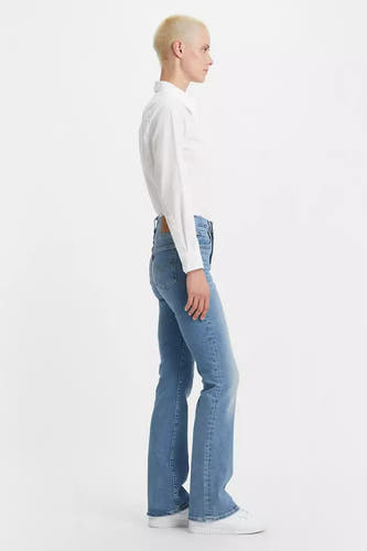 Lichtblauwe bootcut jeans van Levi's, gedragen met een wit overhemd en witte sneakers, in zijaanzicht.
