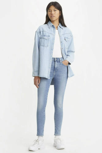 Jean skinny bleu clair de Levi's, associé à un t-shirt blanc et une chemise en denim.