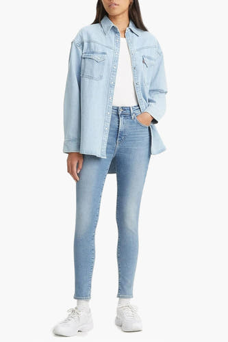 Jean skinny en denim bleu clair de Levi's, associé à une chemise bleu clair et des baskets blanches.