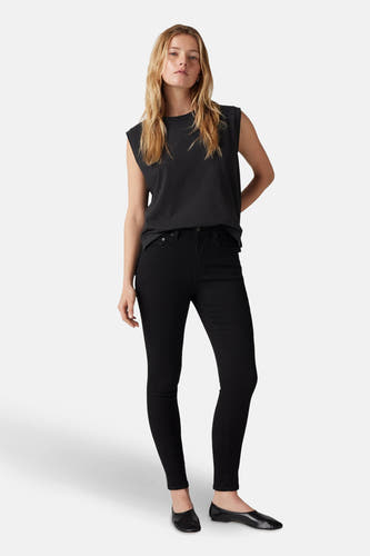 Jean skinny noir de Levi's, porté avec un t-shirt sans manches noir et des chaussures plates.