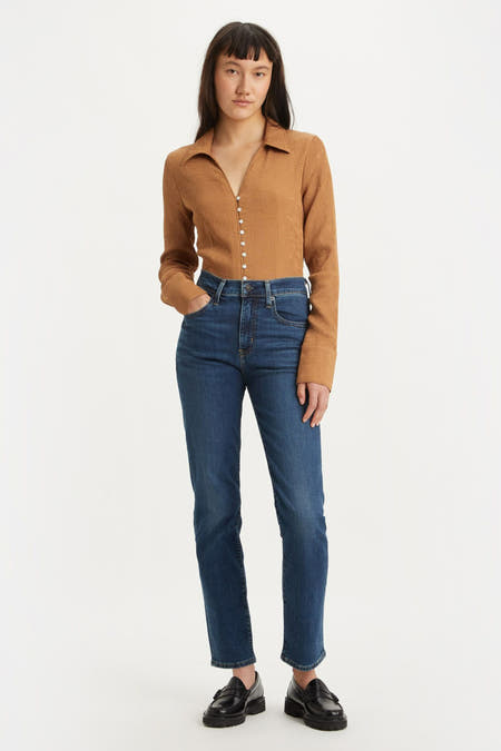 Jean bleu marine droit de Levi's, avec une couleur unie et un style avec une blouse brune et des chaussures noires.