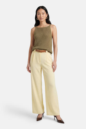 Pantalon jaune de Terra di Siena, avec ceinture marron et jambes larges, combiné avec des escarpins marron et un haut vert.
