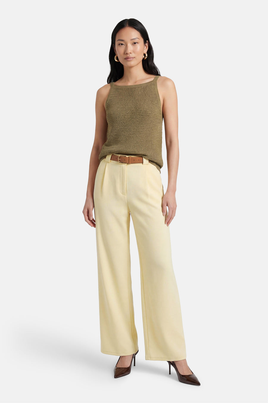 Pantalon jaune de Terra di Siena, avec ceinture marron et jambes larges, combiné avec des escarpins marron et un haut vert.