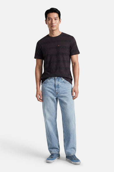 Zwart T-shirt met korte mouwen van Levi's® met subtiele horizontale strepen en borstzakje met rood tab, gedragen met een lichtblauwe jeans.