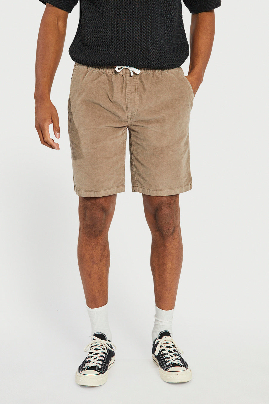Short marron de REDEFINED REBEL, avec cordon de serrage et poches latérales, combiné avec un pull noir, des chaussettes blanches et des baskets noires.