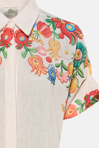 Chemise en lin beige clair à manches courtes de Terra di Siena, avec motif brodé coloré de fleurs et de formes organiques.