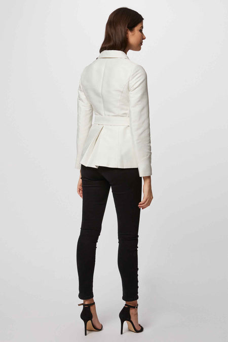 Witte korte jas van Morgan De Toi, met ceintuur, gecombineerd met zwarte skinny jeans en open hakken.