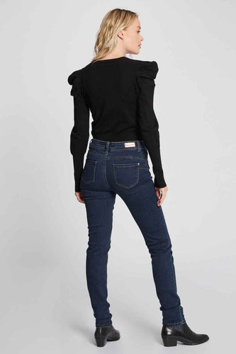 Femme en haut noir et jeans bleu marine, dos, bottes noires.