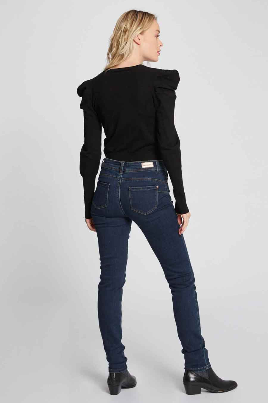 Femme en haut noir et jeans bleu marine, dos, bottes noires.