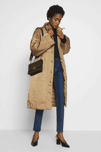 Jean skinny en denim bleu marine de Morgan De Toi, vu de de derrière, associé à une blouse noire et des talons hauts.