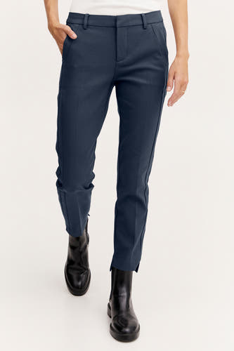 Chino bleu de France, associé à des bottes noires et un chemisier blanc.