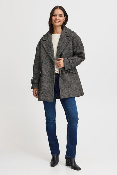 Veste noire de France, avec un motif à carreaux, portée sur une chemise blanche et des jeans bleus.