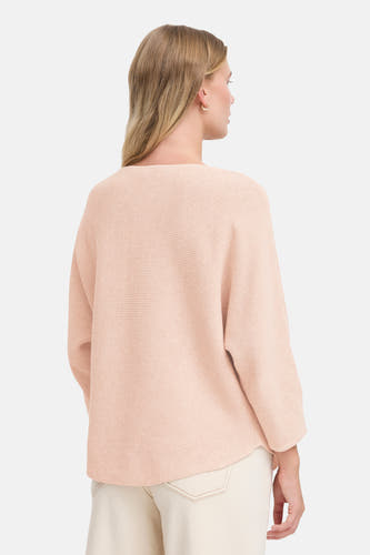 T-shirt rose avec col rond de France, avec une fine structure en côtes et porté avec un pantalon blanc.
