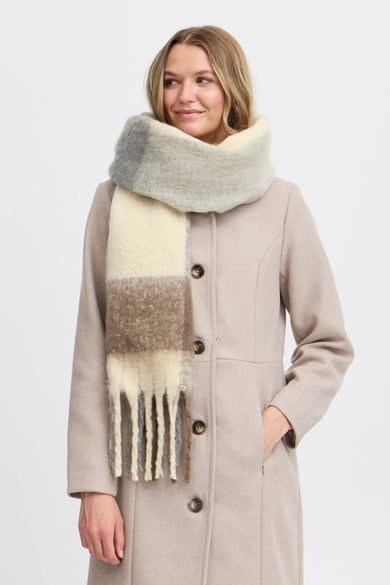 Manteau d'hiver beige de France, avec une grande écharpe rayée en gris, brun et blanc.