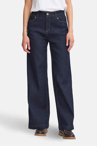 Jean bleu marine large de France, avec des boutons jaunes et des chaussures marron.