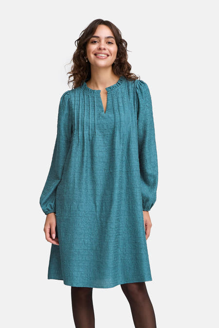 Robe bleue avec des manches longues de France, avec une subtile texture et portée avec un string noir.