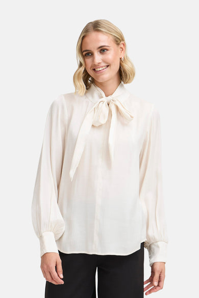 Blouse écru avec longues manches de France, avec détail de cordon au col et manches bouffantes.