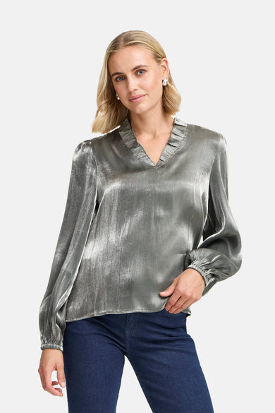 Blouse en argent avec des manches longues de France, avec des plis sur les épaules et portée avec un jean foncé.