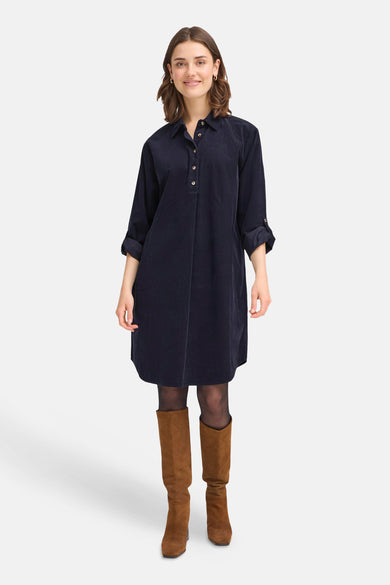 Robe bleue avec des manches longues de France, portée avec des bottes brunes et un string noir.