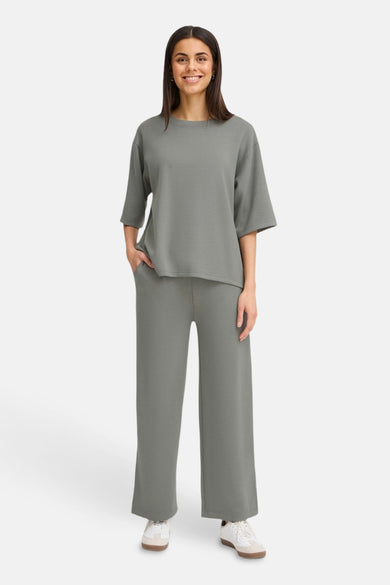 Pantalon kaki français, avec des jambes larges et porté avec un t-shirt coordonné.