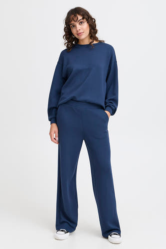 Blauwe joggingbroek van Fransa, met wijde pijpen en gecombineerd met een blauwe sweater en witte sneakers.
