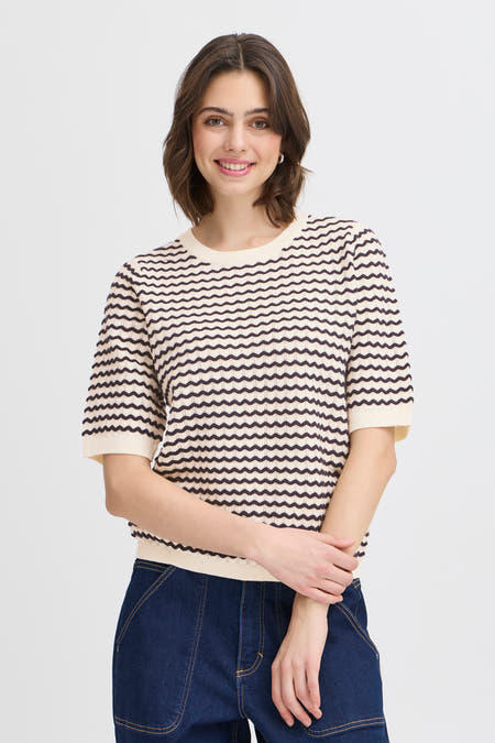 T-shirt bleu de France, avec un motif à rayures ondulées et porté avec un pantalon denim foncé.