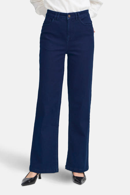 Jean bleu marine, large de France de avec des avec po po et et combiné avec des bottes noires et une chemise blanche.