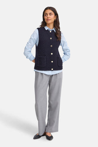 Gilet bleu de France, avec des boutons dorés et des poches, porté sur un chemisier bleu clair et un pantalon gris.