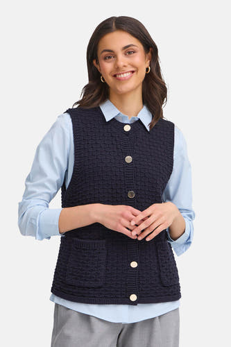 Gilet bleu de France, avec fermeture à boutons, poches et porté sur un chemisier bleu clair.