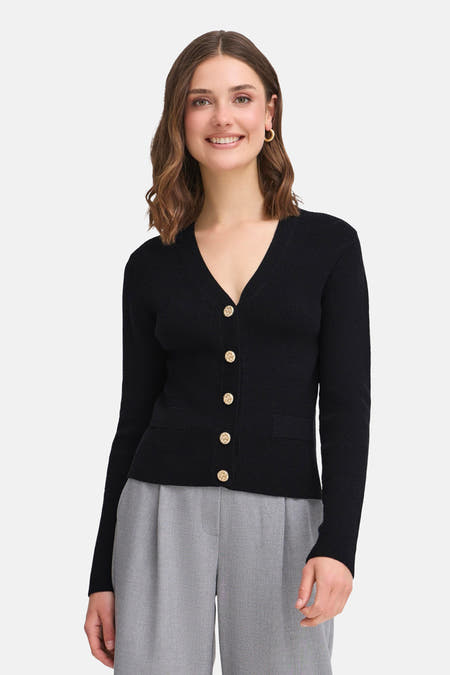 Cardigan noir de France, avec des manches longues et des boutons dorés, associé à un pantalon gris.