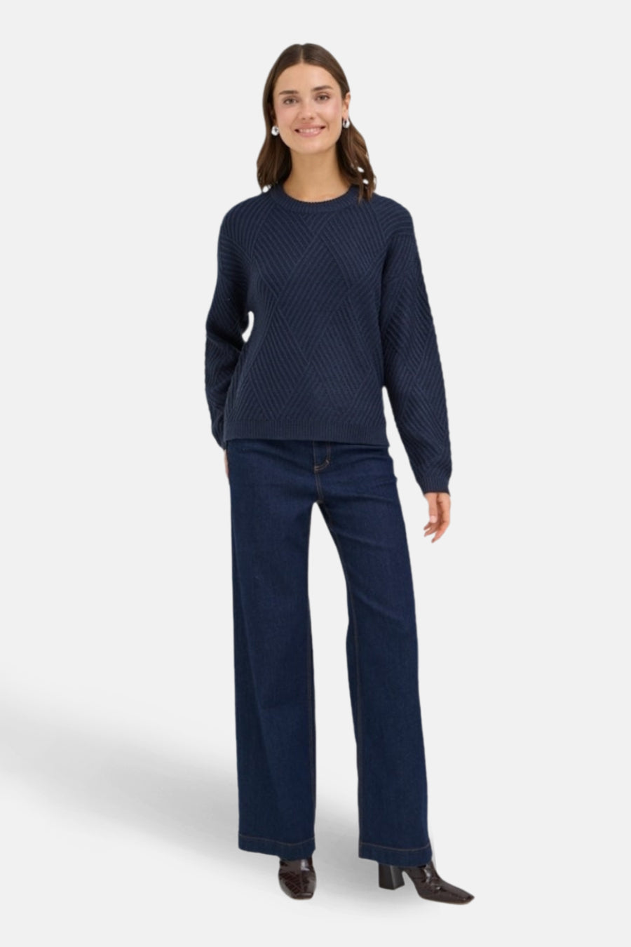 Vrouw met donkerblauwe trui en wijde pijpen jeans.